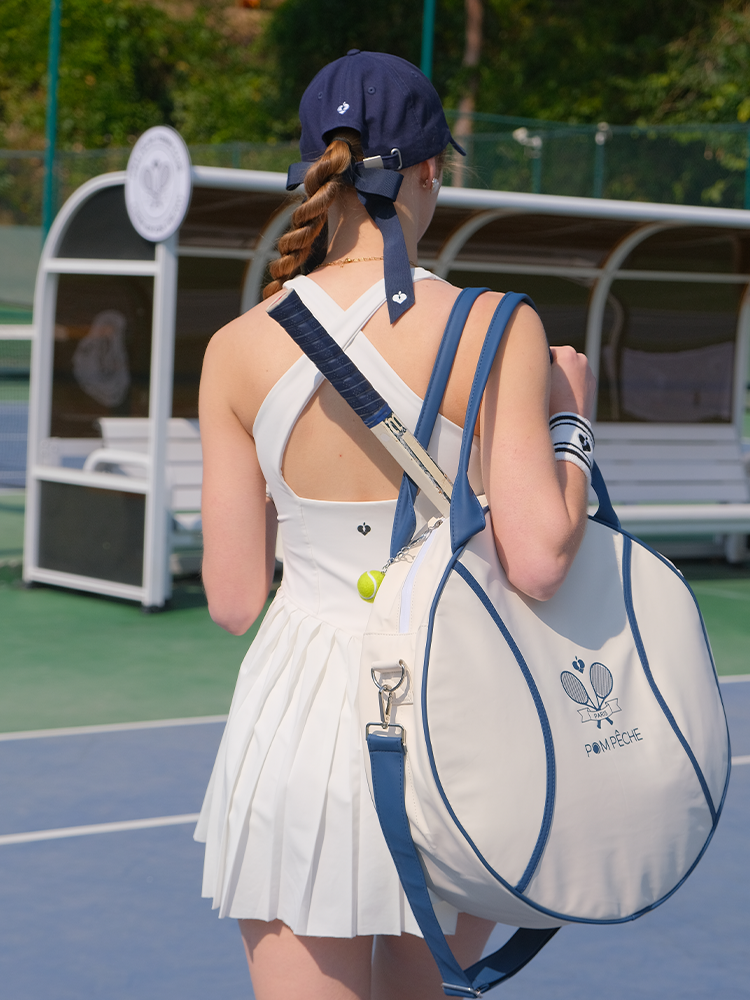 White round tennis bag with blue trim and handles, featuring Pom Pêche logo.