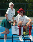 Two women on a tennis court with 'Pompee' branding