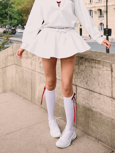 White knee-high tennis socks with red bow detail and logo embroidery.