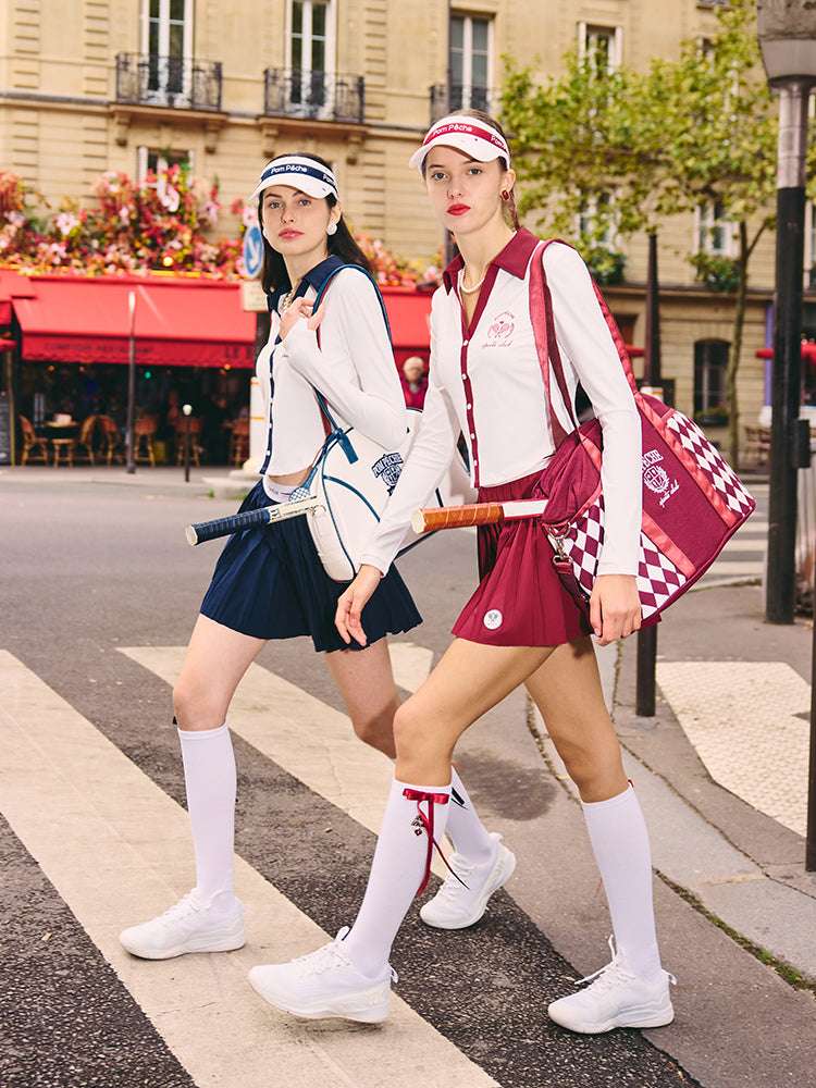 White polo top with red collar and printed logo, worn on the city street for a stylish, casual look.