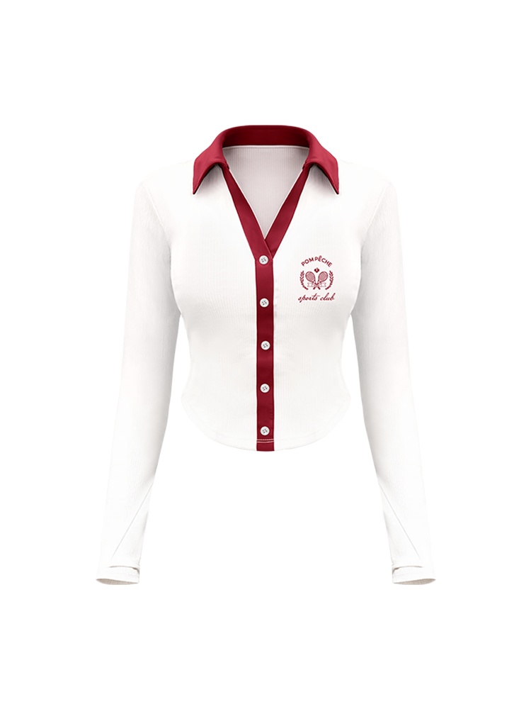 White polo top with red collar and printed logo, worn on the city street for a stylish, casual look.