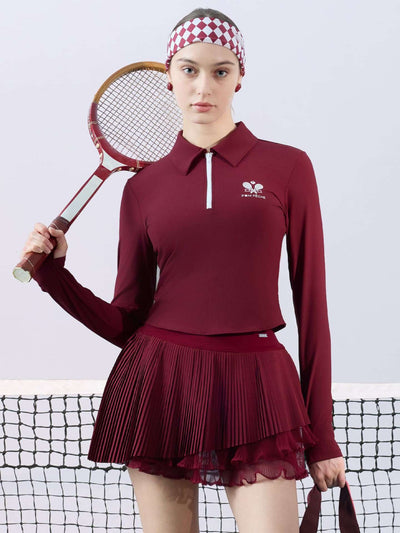 Burgundy pleated tennis skirt paired with long-sleeve top in a court setting