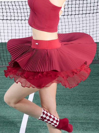 Burgundy pleated tennis skirt displaying wide flare and mesh layers during motion
