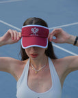 Woman wearing a red visor with a white logo on a tennis court