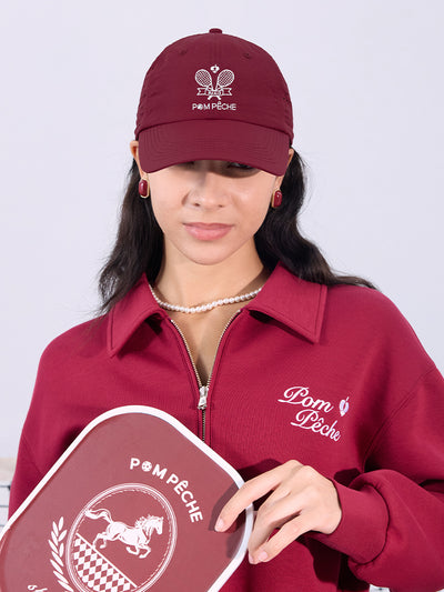 Wine red tennis cap with embroidered logo and adjustable ribbon on the back strap.