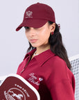 Wine red tennis cap with embroidered logo and adjustable ribbon on the back strap.