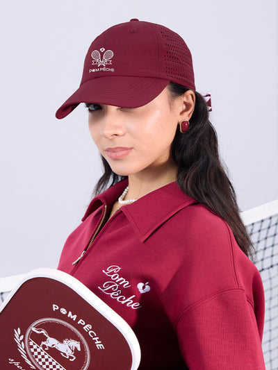 Wine red tennis cap with embroidered logo and adjustable ribbon on the back strap.