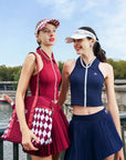 Two women in matching outfits with visors and skirts standing outdoors.