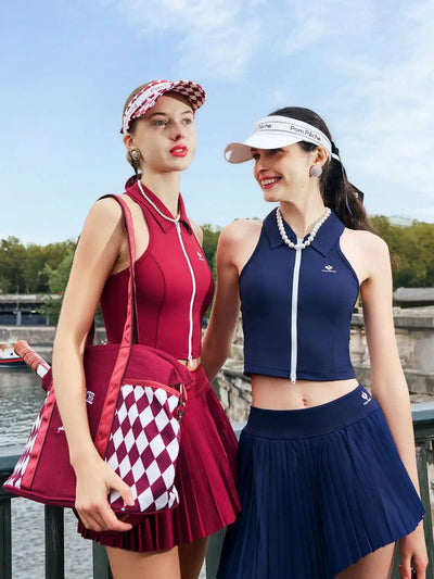 Two women in matching outfits with visors and skirts standing outdoors.
