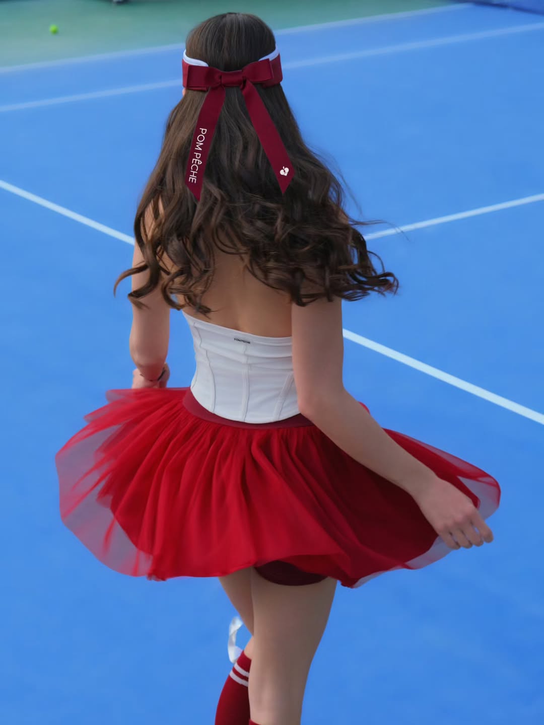 Back view of wine red puff tulle tennis skirt in motion, emphasizing airy volume and high-waisted tennis skirt design on court.