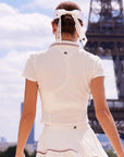 Betty Boop Poise™ Polo Top white, back view showing Pom Pêche logo detail, paired with white pleated tennis skirt, Eiffel Tower Paris editorial