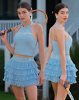 Blue Bow Halter Tennis Top by Pom Pêche, front lifestyle shot with contrast white bow ribbon and halter neckline