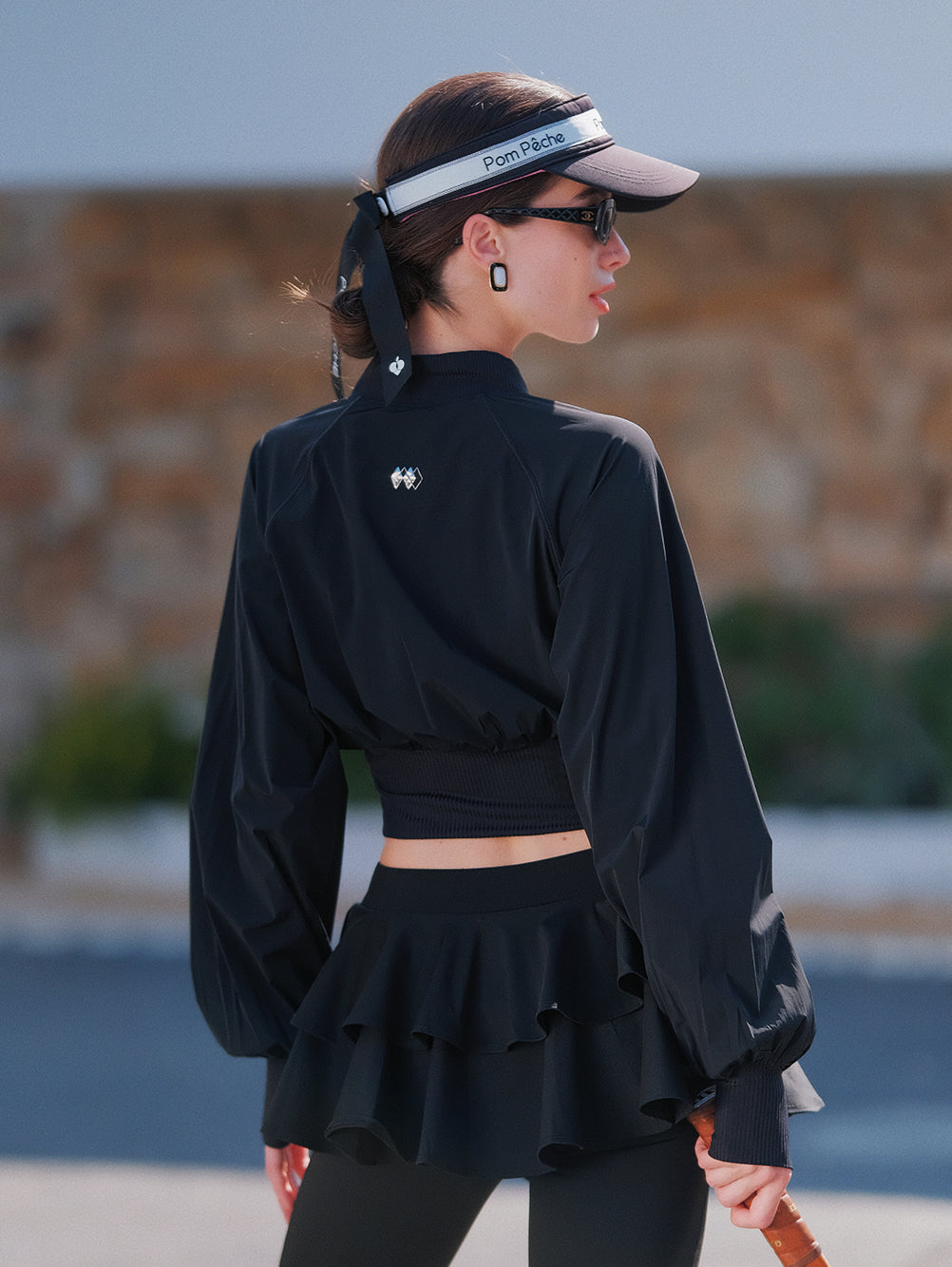 Cropped UV tennis jacket back view in black, fitted waist cinch design with lightweight sporty silhouette
