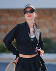Model wearing black cropped UV tennis jacket with dual zipper waist cinch, flattering fitted women’s activewear front view