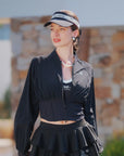 Black cropped UV tennis jacket styled front view, dual zipper waist cinch design for sculpted sporty silhouette