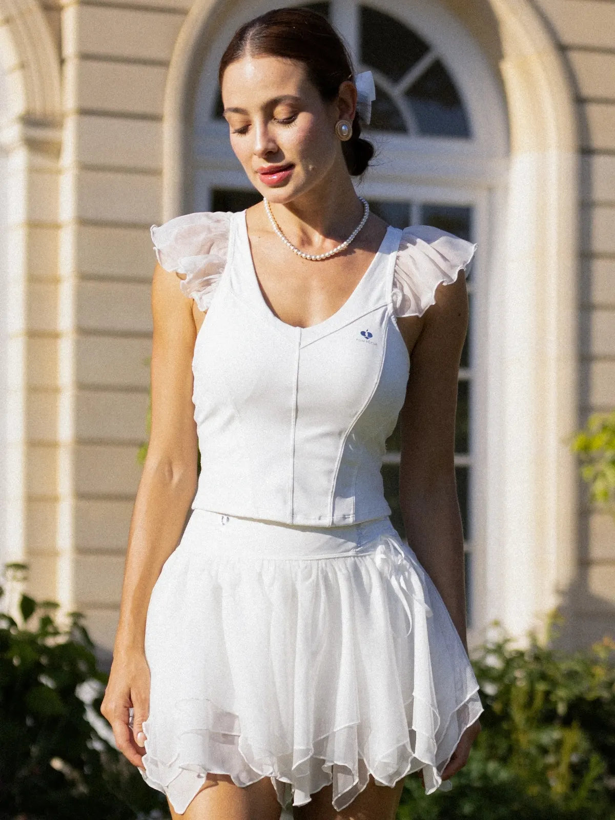 Dopamine V-Neck Performance Tank White on the tennis court, combining breathable comfort, flexible performance, and effortless feminine style