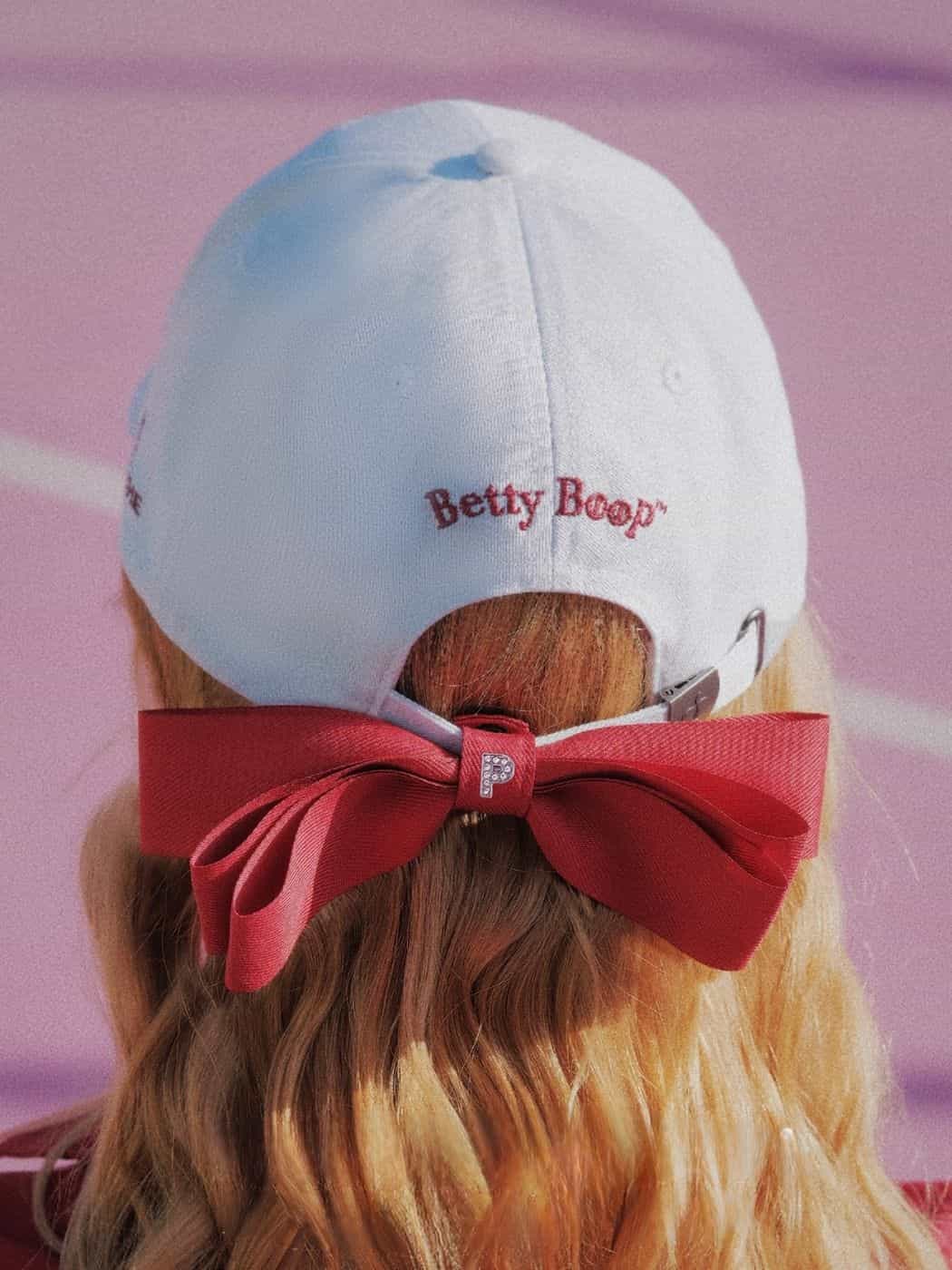 White cap with red bow and 'Betty Boop' logo on a blurred background