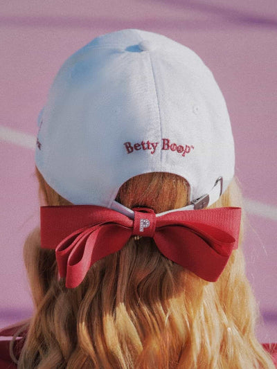 White cap with red bow and 'Betty Boop' logo on a blurred background