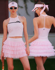 Pink Bow Halter Tennis Top by Pom Pêche, front lifestyle shot with contrast black ribbon bow and sculpting halter neckline