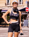 Pom Pêche x Betty Boop black sports tank top styled with matching black shorts and visor on Paris street – women's retro collab athletic top with built-in bra support