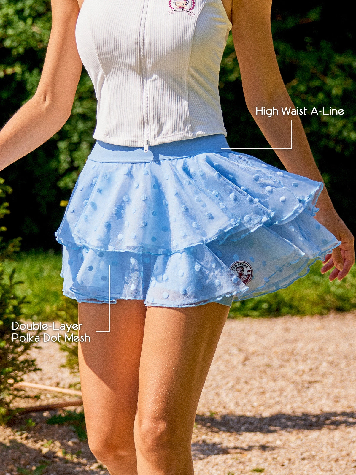 Pom Pêche x Betty Boop Paris blue Cake Skirt feature callout – High Waist A-Line silhouette and Double-Layer Polka Dot Mesh annotated, Betty Boop Pom Pêche circular badge on lower tier, styled with white zip halter top in garden
