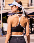 Back view of Pom Pêche x Betty Boop black tank top highlighting breathable mesh racerback design and white contrast trim, worn with Pom Pêche visor on Paris street