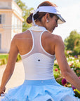 Back view of Pom Pêche x Betty Boop white Poise™ Polo Tank with Racerback Design Accentuates the Shoulder Blades callout – breathable mesh racerback panel with Pom Pêche heart logo, styled with Pom Pêche visor and white bow ribbon in Paris garden