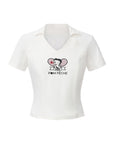 Flat lay of Pom Pêche x Betty Boop Tennis Tee in white – V-neck polo collar, Betty Boop Paris twin-racket graphic with Pom Pêche script, slim-fit short sleeve silhouette with curved hem on white background