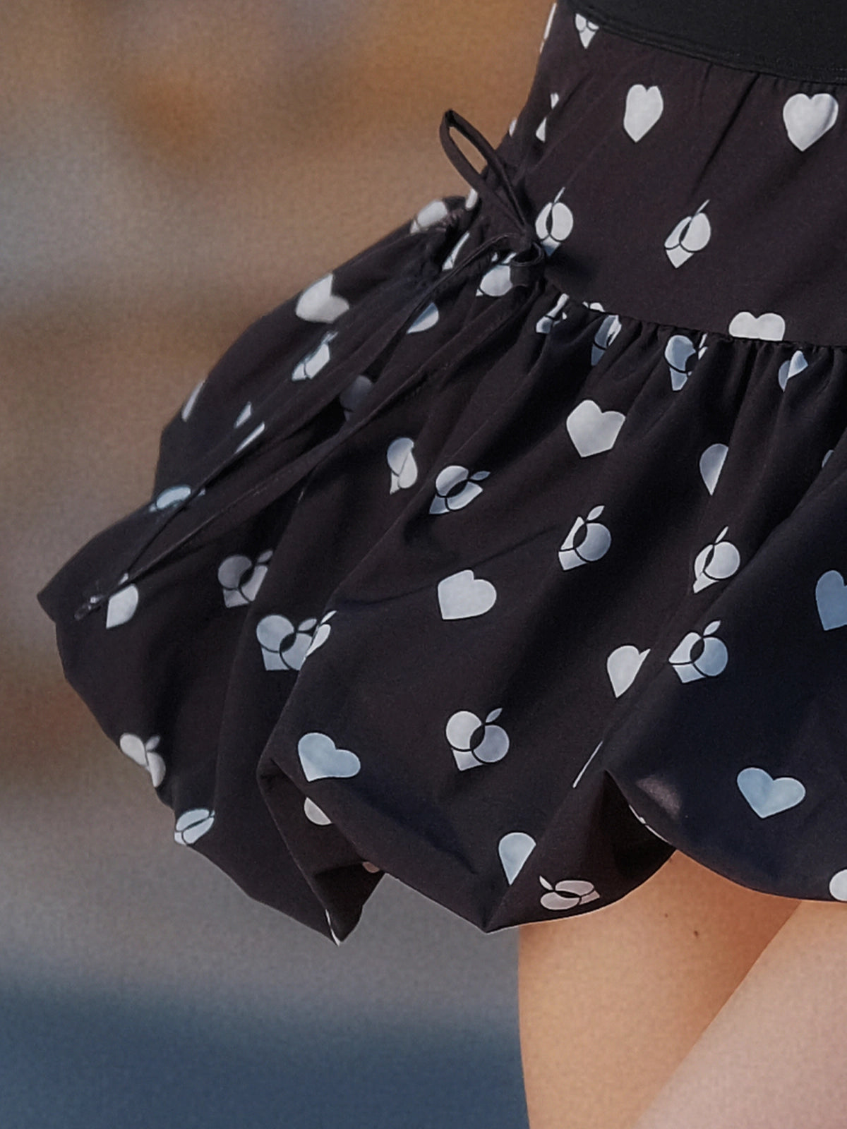 Macro detail of Pom Pêche black Bubble A-Line Skirt showing voluminous bubble hem structure with white heart and Pom Pêche logo allover print – structured polyester-spandex fabric