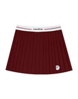 Flat lay of Pom Pêche Classic Pleated Tennis Skirt in wine red – wide white Pom Pêche logo waistband with pink and black stripe, fine knife pleats and Pom Pêche racket badge emblem on white background