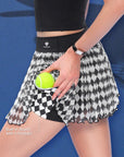 Close-up of Pom Pêche black Diamond Mesh Skirt with Built-In Shorts with 4 Pockets callout – model lifting harlequin diamond mesh skirt to reveal black built-in shorts pocket holding yellow tennis ball, Pom Pêche script waistband