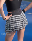 Pom Pêche black Diamond Mesh Skirt feature callout – High-Waisted Flattering Silhouette and Cool-Touch No Ride-Up Comfort annotated, showing wide black waistband with Pom Pêche crown logo and harlequin mesh skirt on blue court