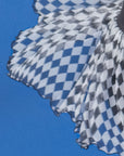 Macro aerial detail of Pom Pêche black Diamond Mesh Skirt showing black and white harlequin diamond print high-density mesh tulle flying against blue sky – ultra-lightweight 0.3g UPF 50+ LYCRA® cool-touch fabric