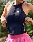 Close-up of Pom Pêche black halter tank highlighting dual-zipper front closure and mesh side pocket storing a gel bottle – key functional features annotated