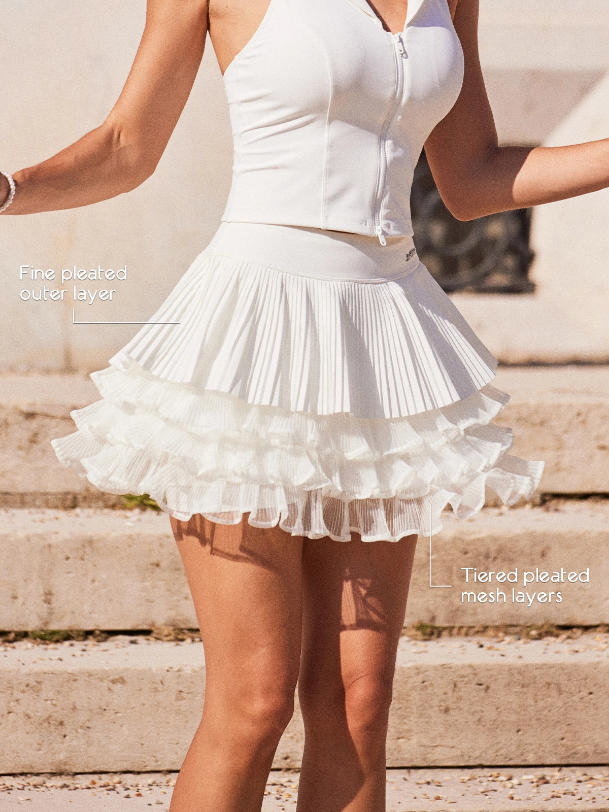 Pom Pêche LaRose tiered tennis skirt feature callout – fine pleated outer layer for hip-slimming effect and three-tier irregular pleated mesh underlayers for airy volume and fluid movement