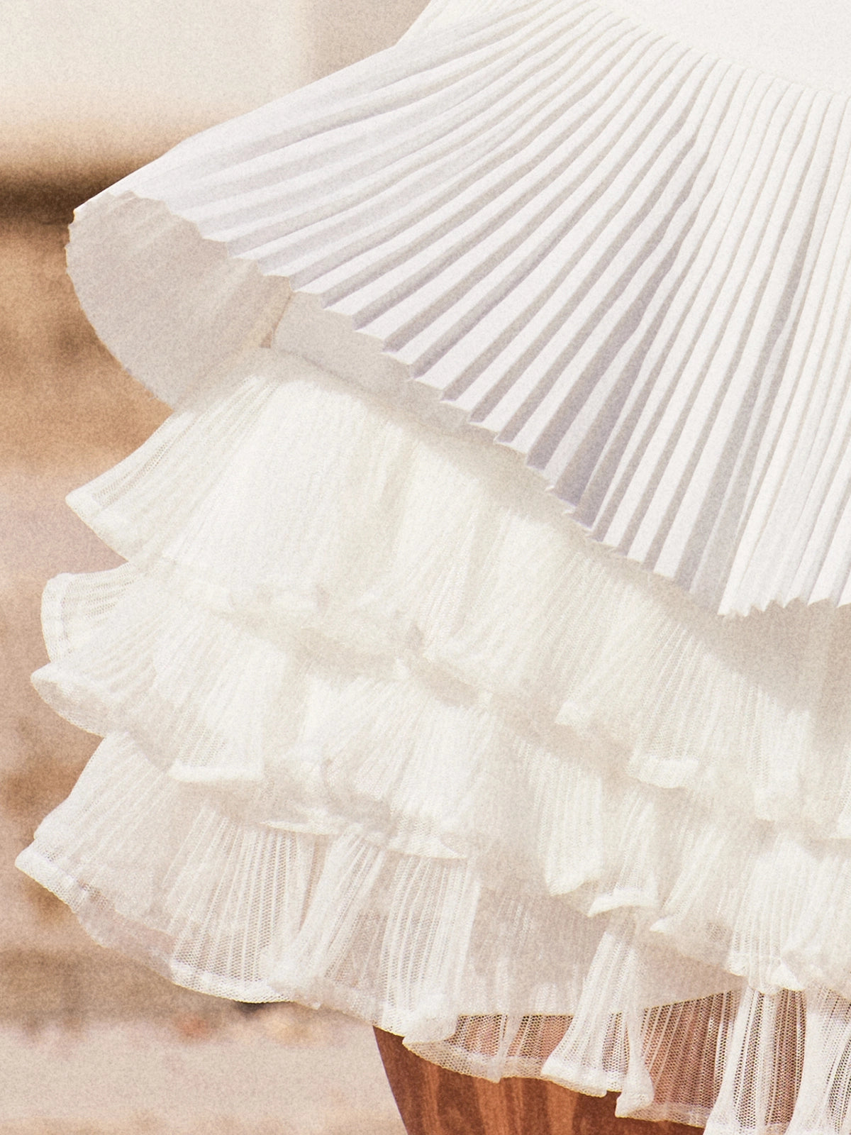 Macro detail of Pom Pêche Spin™ LaRose skirt showing three-layer irregular pleated mesh inner structure – lightweight woven outer layer over airy tiered mesh for elegant volume