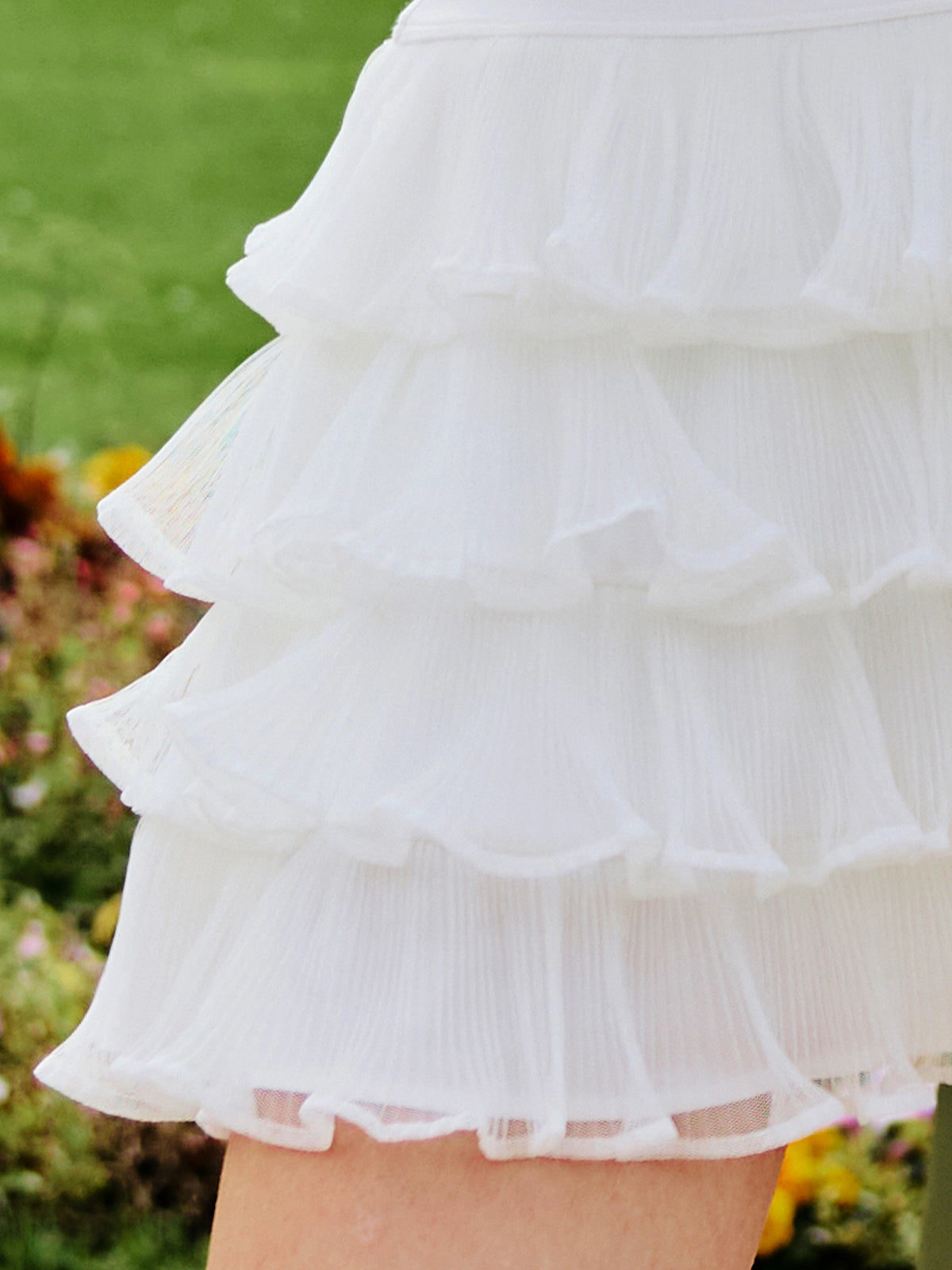 Macro detail of Pom Pêche Spin™ Mille Tiered Skirt showing 4-layer lightweight fine tulle pleats with scalloped ruffle edges – cool-touch breathable fabric for tennis and active wear