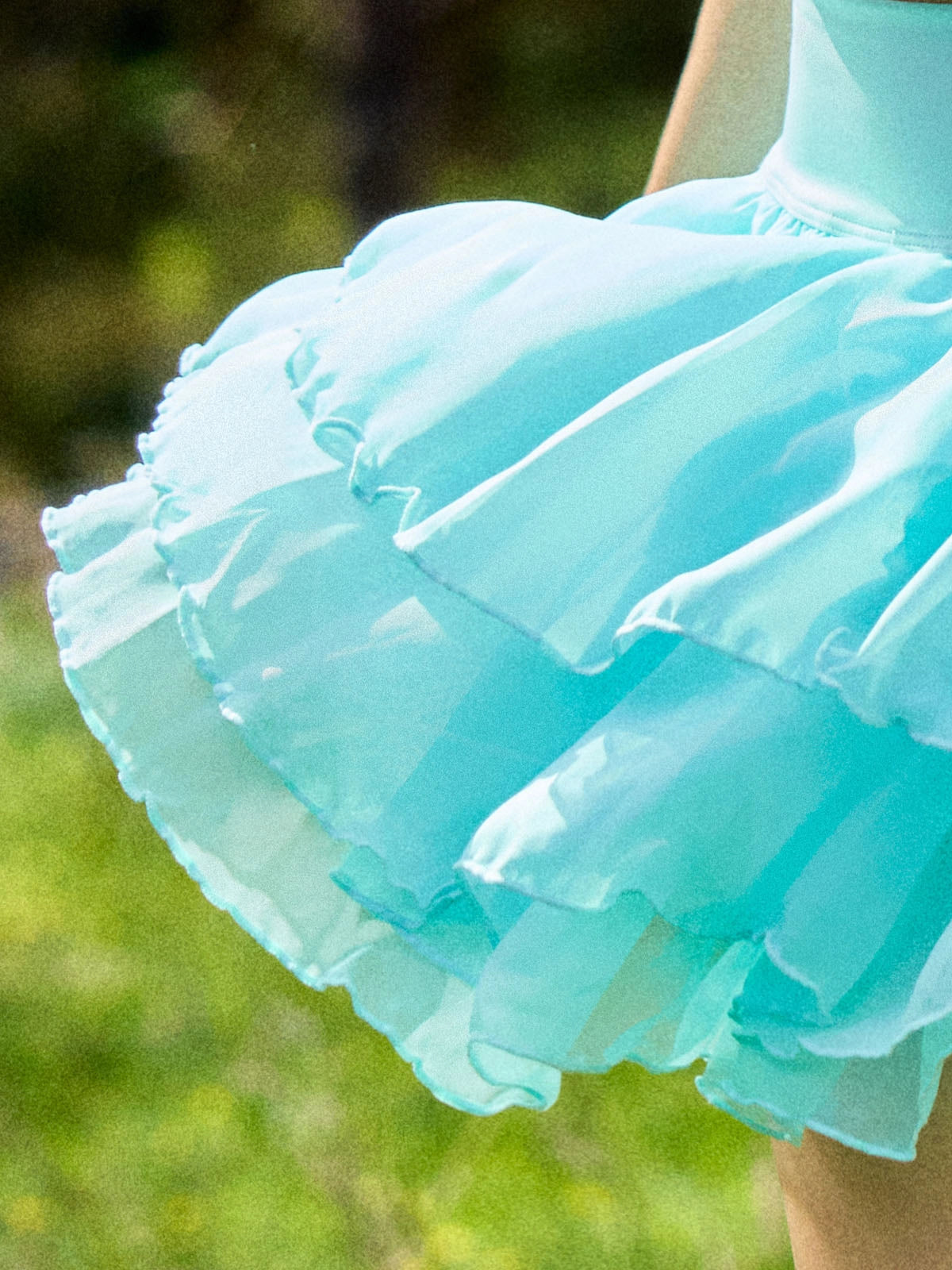 Macro detail of Pom Pêche mint green Petal Tiered Tennis Skirt showing three-layer featherlight chiffon petal tiers with scalloped ruffle edges – semi-sheer airy drape with soft breathable texture