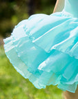Macro detail of Pom Pêche mint green Petal Tiered Tennis Skirt showing three-layer featherlight chiffon petal tiers with scalloped ruffle edges – semi-sheer airy drape with soft breathable texture