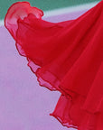 Macro detail of Pom Pêche wine red Petal Tiered Tennis Skirt showing featherlight chiffon layers with scalloped petal ruffle edges flying in motion – semi-sheer airy drape on purple clay court background