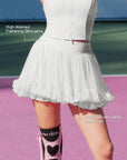 Pom Pêche white Rose Ruffle Skirt feature callout – High-Waisted Flattering Silhouette and Petal-like silhouette that flows annotated, showing airy pleated mesh hem and Pom Pêche logo waistband on pink court