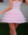 Back view of Pom Pêche pink Ruffle Cake Skirt – 5-layer tulle ruffle tiers flaring with movement, styled with Pom Pêche crown logo pink crop tank on outdoor grass court