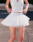 Pom Pêche white Waltz Layered Skirt feature callout – High-Waisted Design and Multi-Layer Asymmetrical Pleats annotated, model pulling waistband showing sculpting high-waist band with Pom Pêche metal tag and double-layer asymmetric pleated hem on outdoor court