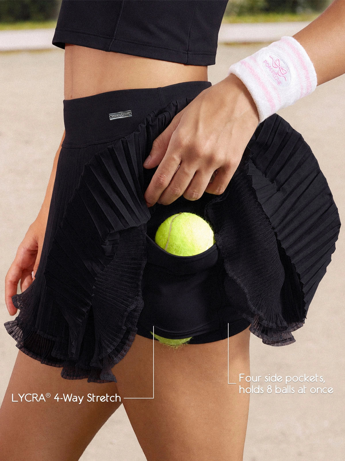 Close-up of Pom Pêche black Waltz tennis skirt showing LYCRA® 4-way stretch built-in shorts with four side pockets holding 8 tennis balls – Pom Pêche metallic logo waistband detail