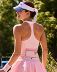 Back view of Pom Pêche blush pink Zip-Neck Halter Tank with feature callouts – open Racerback Cut for unrestricted movement and Back Pocket holding phone annotated, Pom Pêche logo detail, Paris garden background