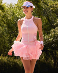 Full body view of Pom Pêche Zip-Neck Halter Racerback Tank in blush pink – high halter neckline, white front zip closure and fitted silhouette, styled with matching pink Rose Ruffle Skirt and Pom Pêche visor in Paris garden