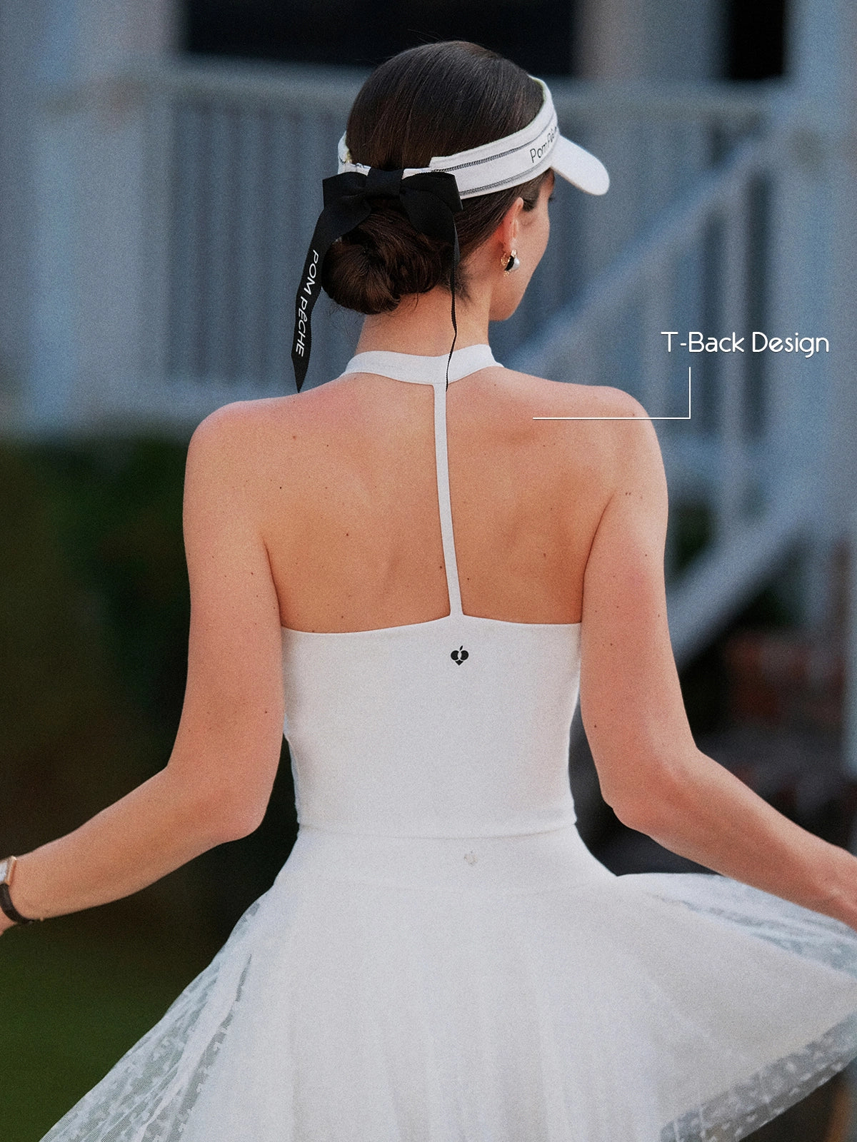 White Bow Halter Tennis Top T-back open-back design, flattering halter T-strap and Pom Pêche logo back detail, worn with Pom Pêche visor